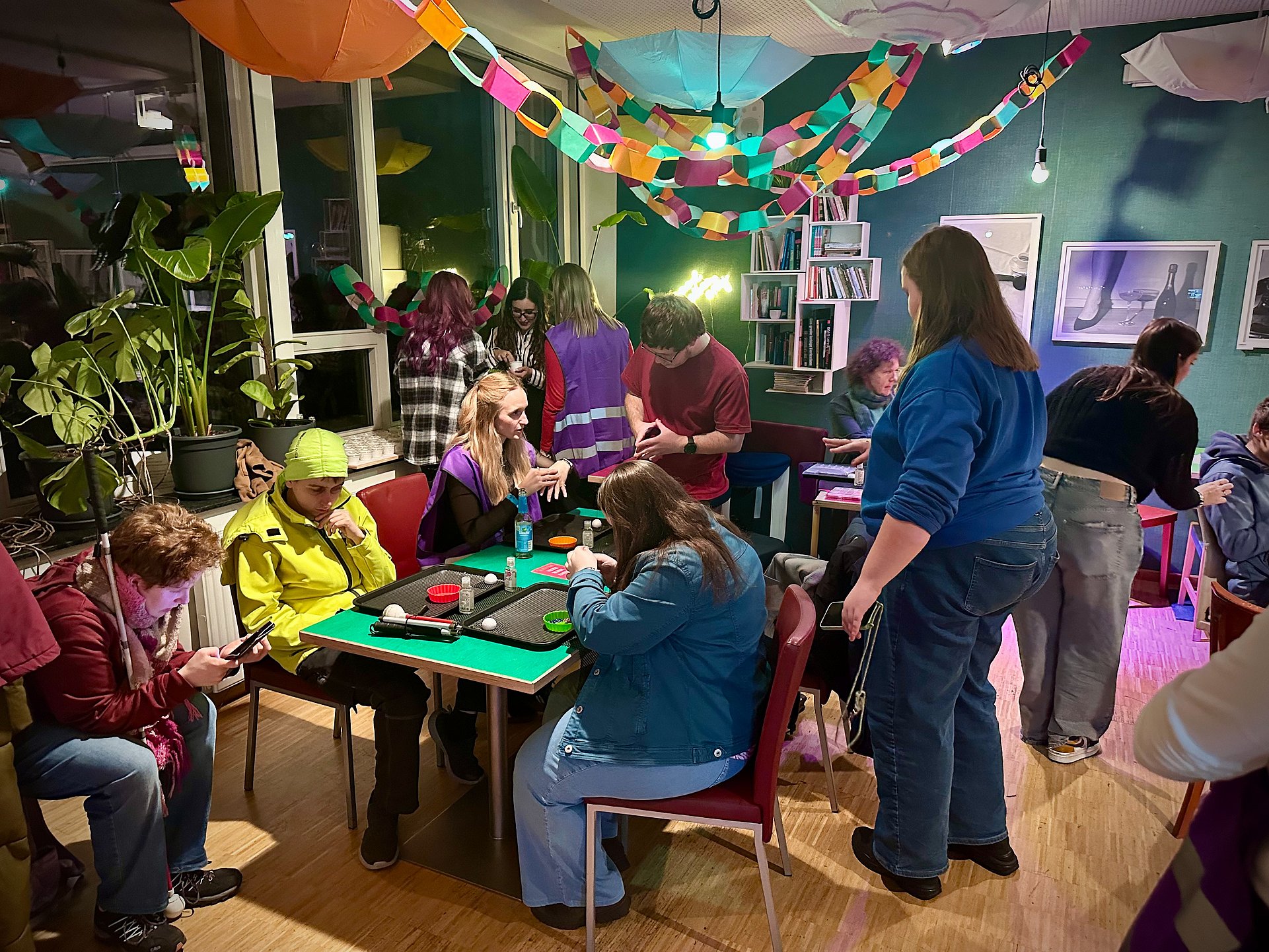 Viele junge Menschen sitzen und stehen in einem bunt dekorierten Zimmer