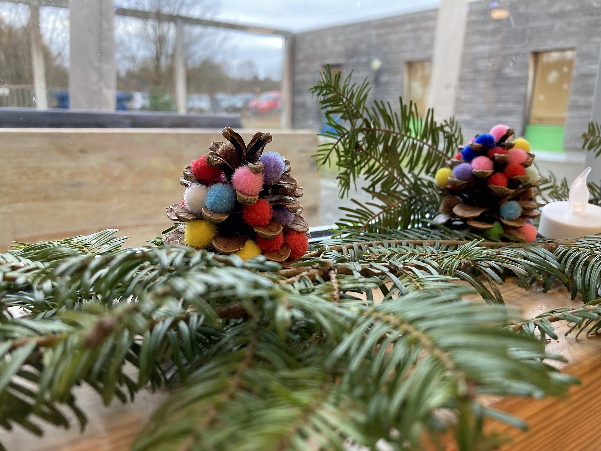 Tannenzweige auf denen bunt dekorierte Tannenzapfen liegen