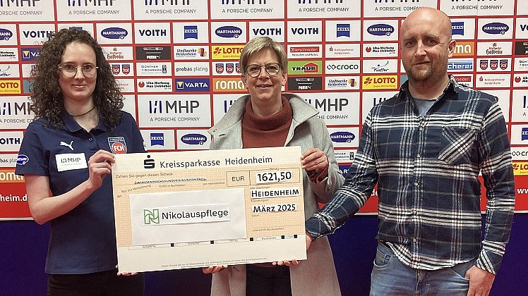 Tatjana Müller vom 1. FC Heidenheim, Gesina Wilfert und Stefan Schiefelbein von der Nikolauspflege in Heidenheim halten den Spendenscheck in der Hand.