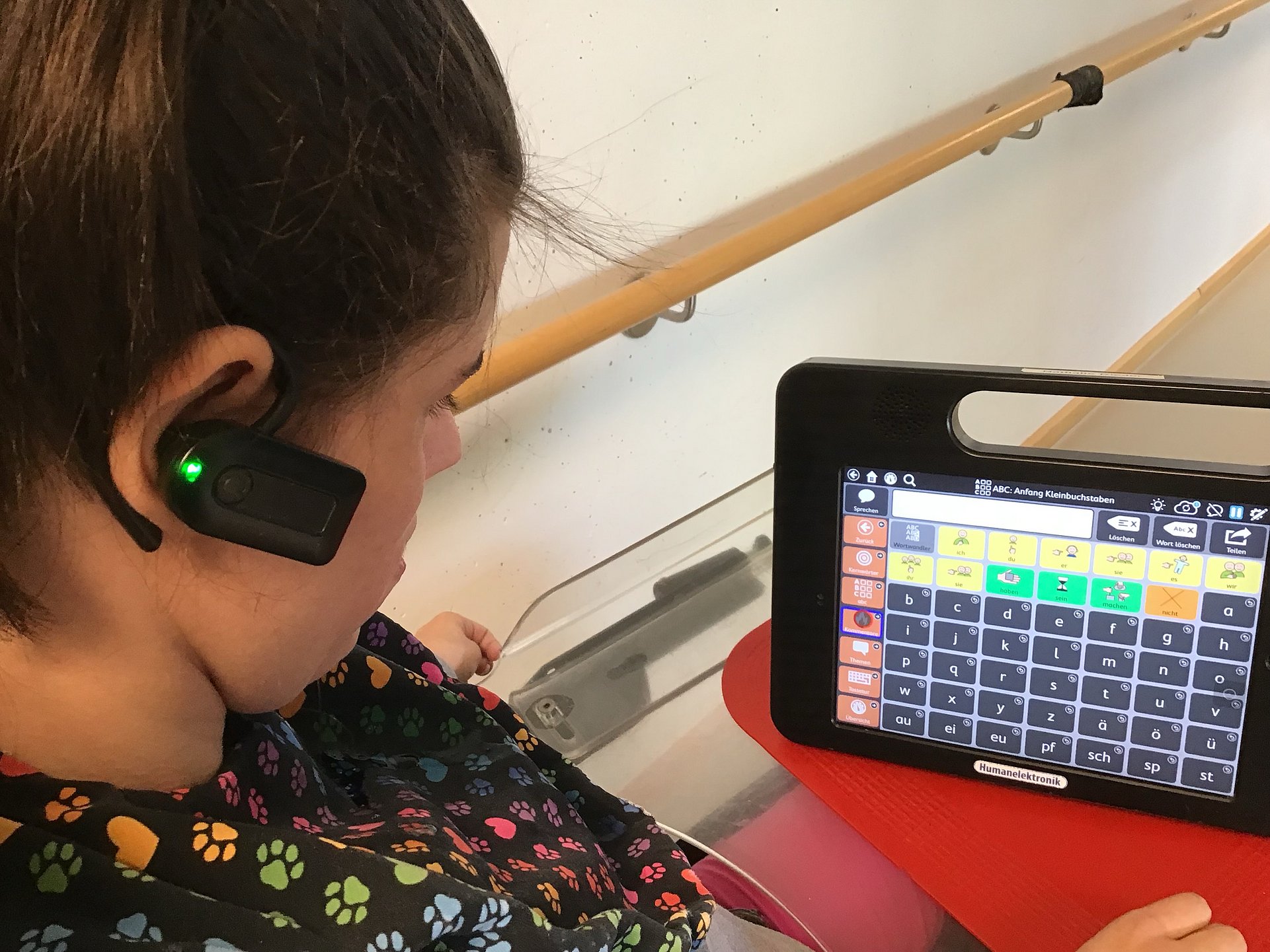 Eine Klientin arbeitet an einem Tablet. Sie trägt ein Hörgerät