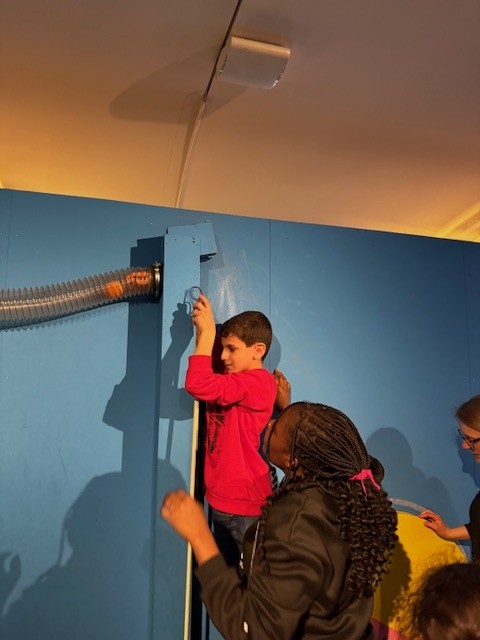 Ein Junge und ein Mädchen probieren eine interaktive Installation in der Ausstellung aus