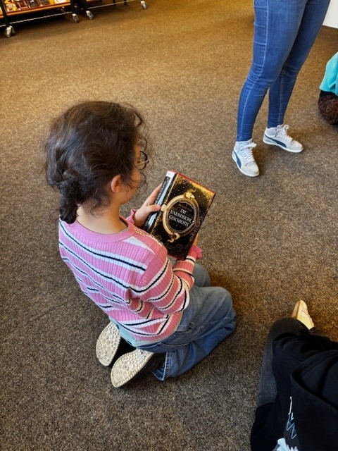 Ein Mädchen sitzt auf dem Boden. In ihren Händen hält sie ein Buch